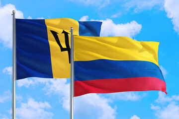 Colombia and Barbados national flag waving in the windy deep blue sky. Diplomacy and international relations concept.