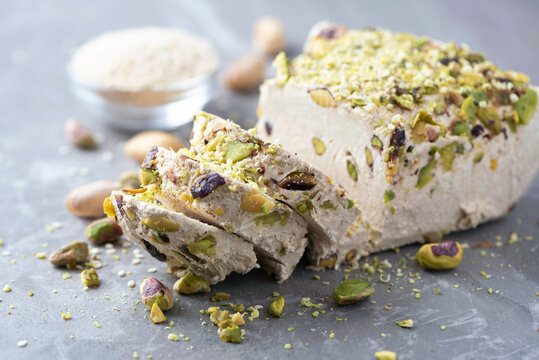 Sesame halva with pistachios on grey background. Top view. Copy space. Traditional middle eastern sweets. Jewish, turkish, arabic national dessert. Turkish delight