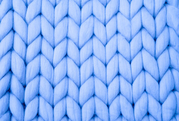 Knitted background. Knitted fabric made of light blue Merino wool. Large weave. Pattern of pigtails.