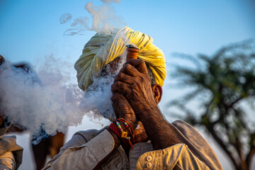 a rajasthani tribal man smoking chillam at pushkar