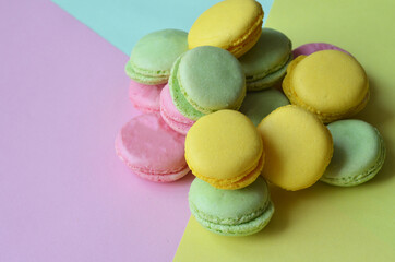 Mixed of colorful macaroni or pasta cake on a yellow pink blue background. Sweet and colorful french macarons, pastel colors. Flat lay, top view.