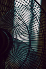 A fan in a dark empty room against a window