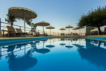 Empty sunbeds by a swimming pool with evening sun