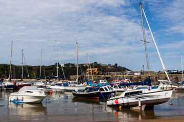 Fototapeta na wymiar Boats resting on the sand at lowtide in the picturesque harbour and seaside town of Tenby in Wales