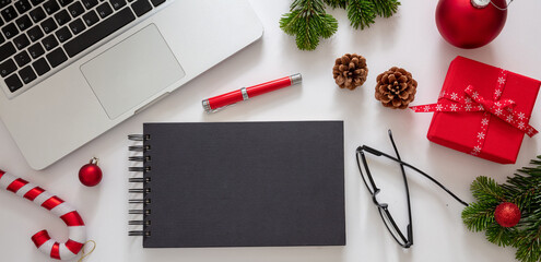 Christmas, office closed. Black notepad, laptop and xmas decoration, white background