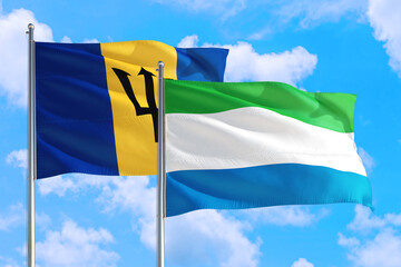Sierra Leone and Barbados national flag waving in the windy deep blue sky. Diplomacy and international relations concept.