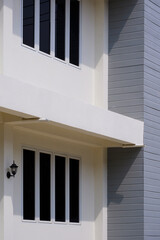 Sunlight and shadow on glass windows surface outside of 2-story house building wall