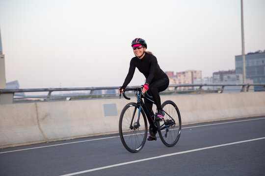 View of a girl exercising on a bicycle in the city in the morning at dawn. St. Petersburg Krestovsky Island Yakhtenny Bridge.