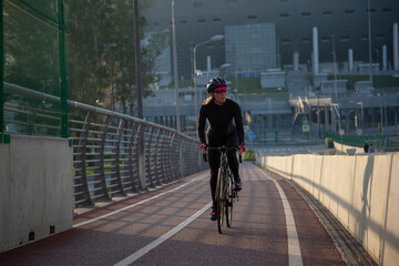 Evening workout of a woman on a bike. Play sports in the city. Yacht Bridge St. Petersburg.