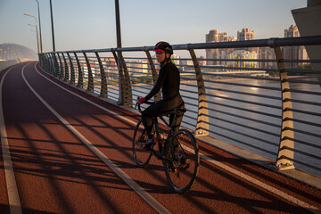 Rest after cycling. A woman stands with a bicycle and looks at the camera. Cycling in the city in the evening at sunset.