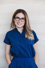Mexican woman with glasses wearing blue doctor uniform and smiling Latin America
