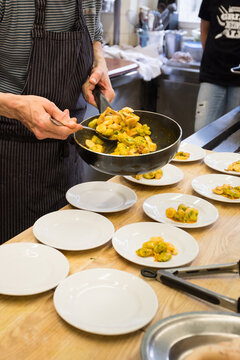 Human hands placing gnocchi with ramson on small plates as starter dish