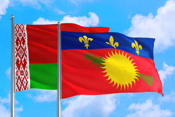 Guadeloupe and Belarus national flag waving in the windy deep blue sky. Diplomacy and international relations concept.