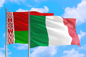Naklejka na ściany i meble Italy and Belarus national flag waving in the windy deep blue sky. Diplomacy and international relations concept.