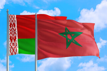 Fototapeta na wymiar Morocco and Belarus national flag waving in the windy deep blue sky. Diplomacy and international relations concept.