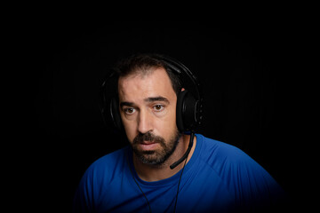 Fototapeta premium Bearded man dressed in blue t-shirt and with headphones posing on black background