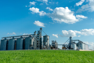Obraz premium silver silos on agro manufacturing plant for processing drying cleaning and storage of agricultural products, flour, cereals and grain. Large iron barrels of grain. Granary elevator
