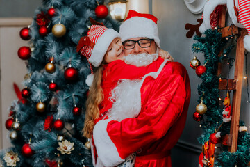 Fototapeta na wymiar Happy cheerful child hugs Santa Claus with his eyes closed. Santa Claus and children.