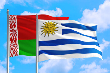 Uruguay and Belarus national flag waving in the windy deep blue sky. Diplomacy and international relations concept.