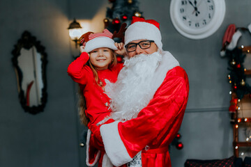 Fototapeta premium The child is in Santa's arms. New year for children. Meeting with Santa.