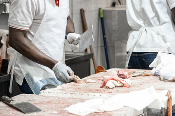 African american butcher cutting meat at counter in butchery. A man cook cut fresh bacon meat