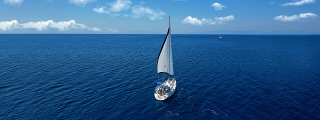 Aerial drone ultra wide panoramic photo of beautiful sailboat cruising the Aegean deep blue sea