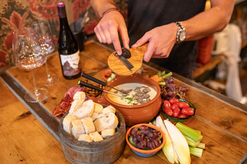 Truffle grated over a pan of cheese fondue on a table with fresh fruit and vegetables