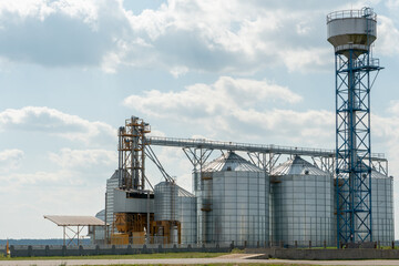silver silos on agro manufacturing plant for processing drying cleaning and storage of agricultural products, flour, cereals and grain. Large iron barrels of grain. Granary elevator