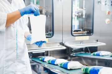 Dairy operator holds bags of packaged milk in hands. Automatic filling conveyor