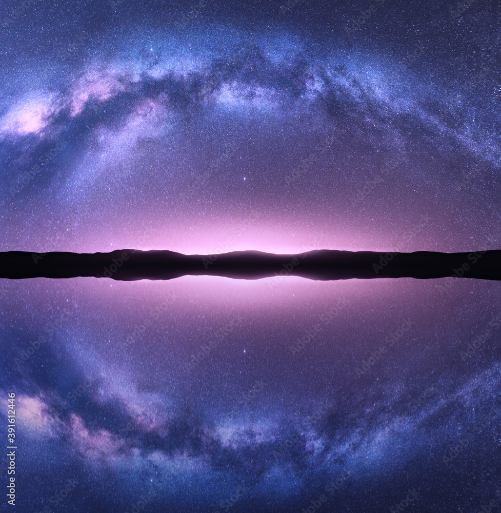 Wall mural milky way arch reflected in water. night landscape with bright arched milky way, purple sky with sta