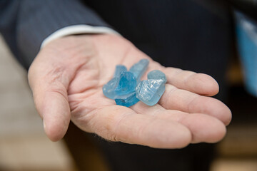 Jeweler holds natural colorless and blue topaz in his hand
