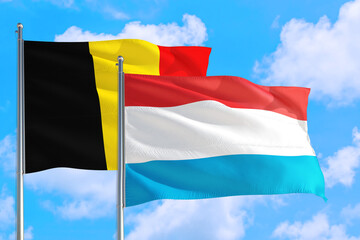 Luxembourg and Belgium national flag waving in the windy deep blue sky. Diplomacy and international relations concept.