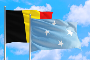 Micronesia and Belgium national flag waving in the windy deep blue sky. Diplomacy and international relations concept.
