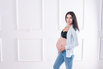 Fototapeta na wymiar Happy pregnant girl in jeans and unbuttoned shirt