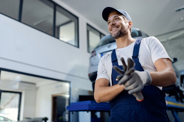 Below view of happy mechanic working at auto repair shop.