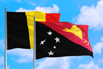 Papua New Guinea and Belgium national flag waving in the windy deep blue sky. Diplomacy and international relations concept.