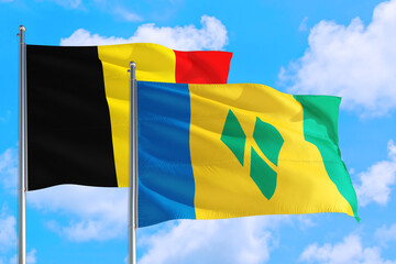 Saint Vincent And The Grenadines and Belgium national flag waving in the windy deep blue sky....