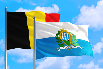 San Marino and Belgium national flag waving in the windy deep blue sky. Diplomacy and international relations concept.