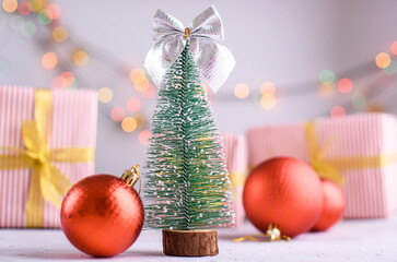 New Year's card on a bright background. Little eve tree, Christmas tree balls, lights.