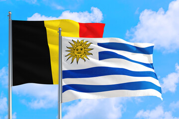 Uruguay and Belgium national flag waving in the windy deep blue sky. Diplomacy and international relations concept.