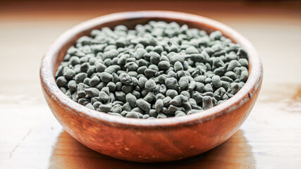 Chinese tea ginseng oolong in the form of small stones in a wooden plate, close-up with a blurred background. 
