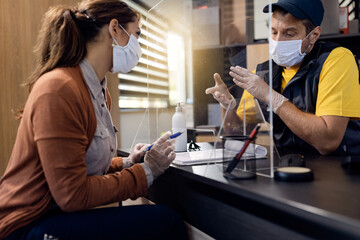 Fototapeta premium Auto repairman communicating with a customer while wearing protective face mask and gloves in the office.