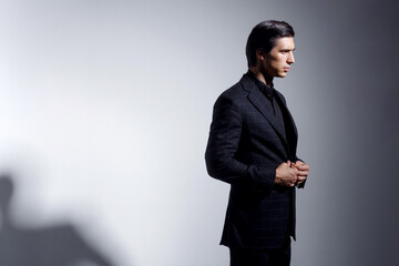 Obraz na płótnie Canvas Portrait of handsome young man in black stylish suit, over on dark grey background.