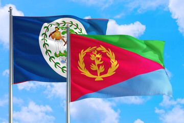 Fototapeta na wymiar Eritrea and Belize national flag waving in the windy deep blue sky. Diplomacy and international relations concept.