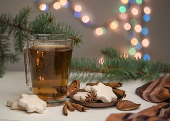 Cup with tea, spices and Christmas tree branches on a bokeh background.