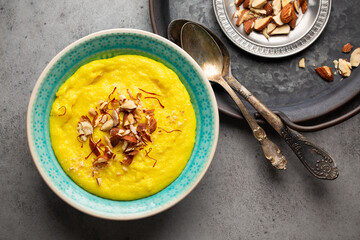 Traditional Indian dish Kheer, sweet rice milk pudding with almonds and saffron in blue ceramic...