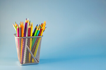 Pencils in the holder are isolated on blue background. Flat lay, top view. Copy space. Back to school.