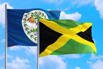 Jamaica and Belize national flag waving in the windy deep blue sky. Diplomacy and international relations concept.