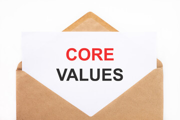 A white sheet with the text core values lies in an open craft envelope on a white background with copy space. Business concept image