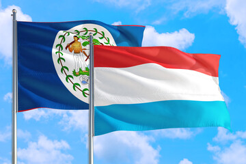 Luxembourg and Belize national flag waving in the windy deep blue sky. Diplomacy and international relations concept.